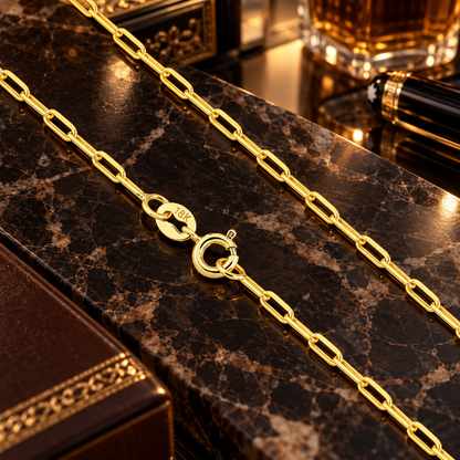 Detalhe em aproximação da corrente estilo Cartier banhada a ouro 18k destacando o fecho boia redondo e a gravação de autenticidade 18K sobre superfície de mármore escura.