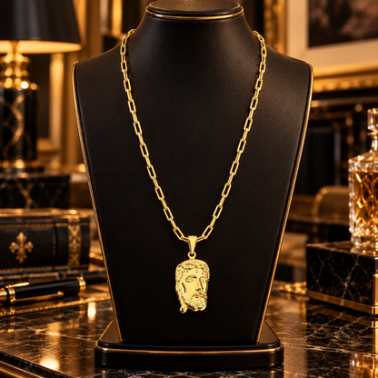 Colar masculino banhado a ouro 18k com corrente Cartier e pingente grande da Face de Cristo exibido em um busto expositor preto de joias.