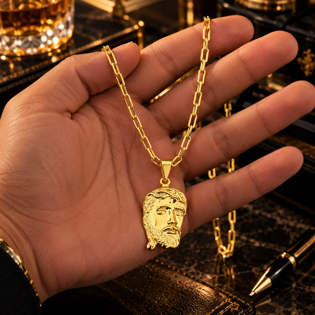 Mão masculina segurando a corrente Cartier banhada a ouro 18k com o pingente grande da Face de Cristo para visualização de tamanho e escala.