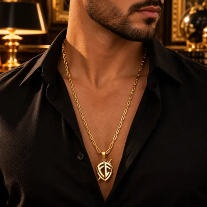 Homem vestindo camisa preta aberta usando o Colar Masculino Cartier Fecho Canhão Com Pingente Escudo de Fé Banhada a Ouro 18k no pescoço.