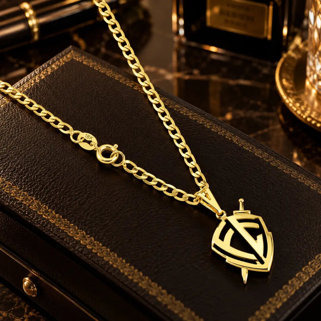 Colar masculino banhado a ouro 18k em corrente Grumet com fecho redondo com timbre 18K e pingente em formato de escudo da fé com espada sobre estojo de couro.