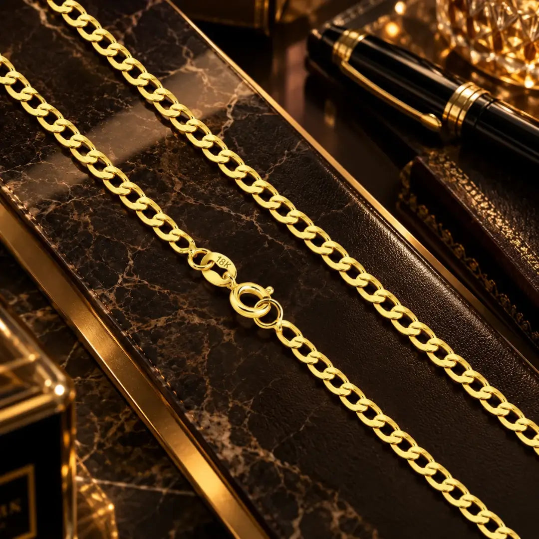 Detalhe em aproximação da corrente masculina banhada a ouro 18k em elos Grumet com fecho redondo e gravação 18K sobre superfície de mármore escura.