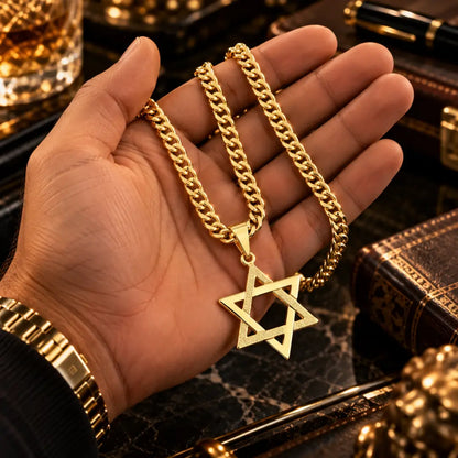 Mão masculina segurando o colar banhado a ouro 18k com corrente grumet dupla e o pingente de Estrela de Davi para demonstração de escala e tamanho.