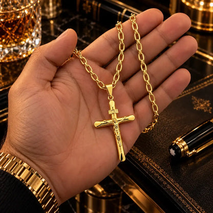 Mão masculina segurando o colar banhado a ouro 18k com corrente grumet longa e pingente de crucifixo INRI para visualização de proporção e tamanho.