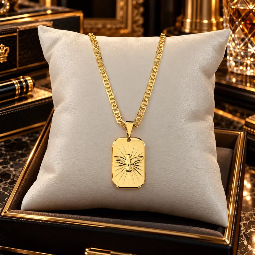 Colar masculino com corrente piastrini e pingente medalha do Espírito Santo banhados a ouro 18k apoiados sobre uma almofada de veludo clara.