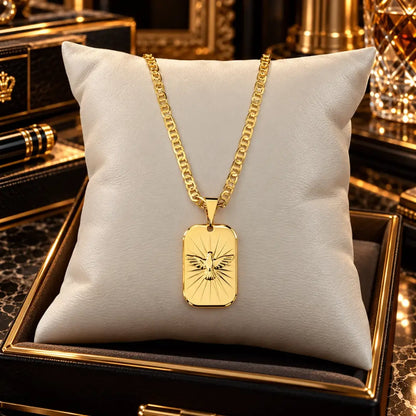 Colar masculino com corrente piastrini e pingente medalha do Espírito Santo banhados a ouro 18k apoiados sobre uma almofada de veludo clara.