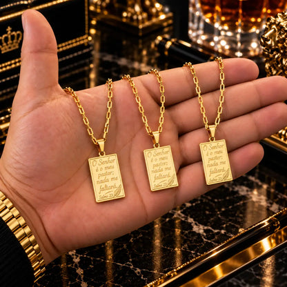 Três colares masculinos Salmos 23 banhados a ouro 18K sobre a palma da mão, destacando os pingentes e as correntes.