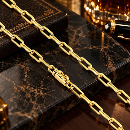 Detalhe em aproximação da corrente estilo Cartier banhada a ouro 18k com espessura de 4.5mm destacando o fecho canhão reforçado sobre mármore.