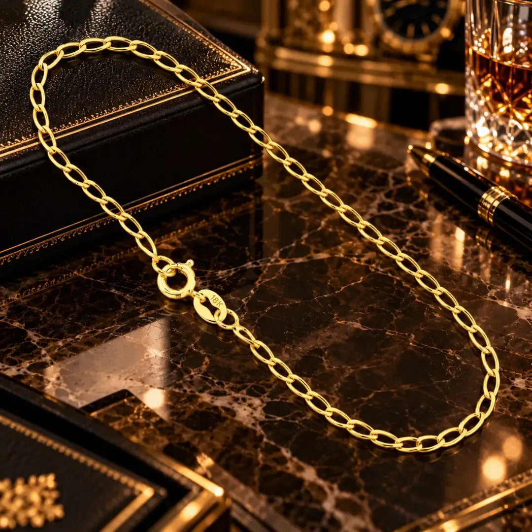 Vista superior da pulseira masculina banhada a ouro 18k com elos grumet longos de 2.5mm e fecho boia estendida sobre superfície de mármore luxuosa.